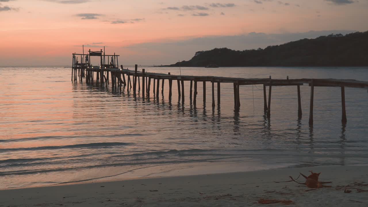 puesta de sol sobre un muelle de madera en una playa tropical