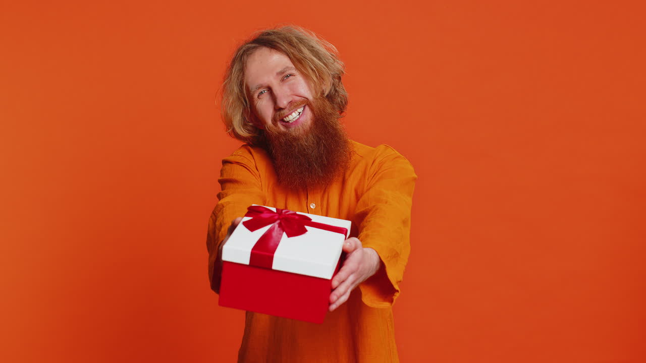 Smiling young man presenting birthday gift present box stretches out hands promotion discount sale