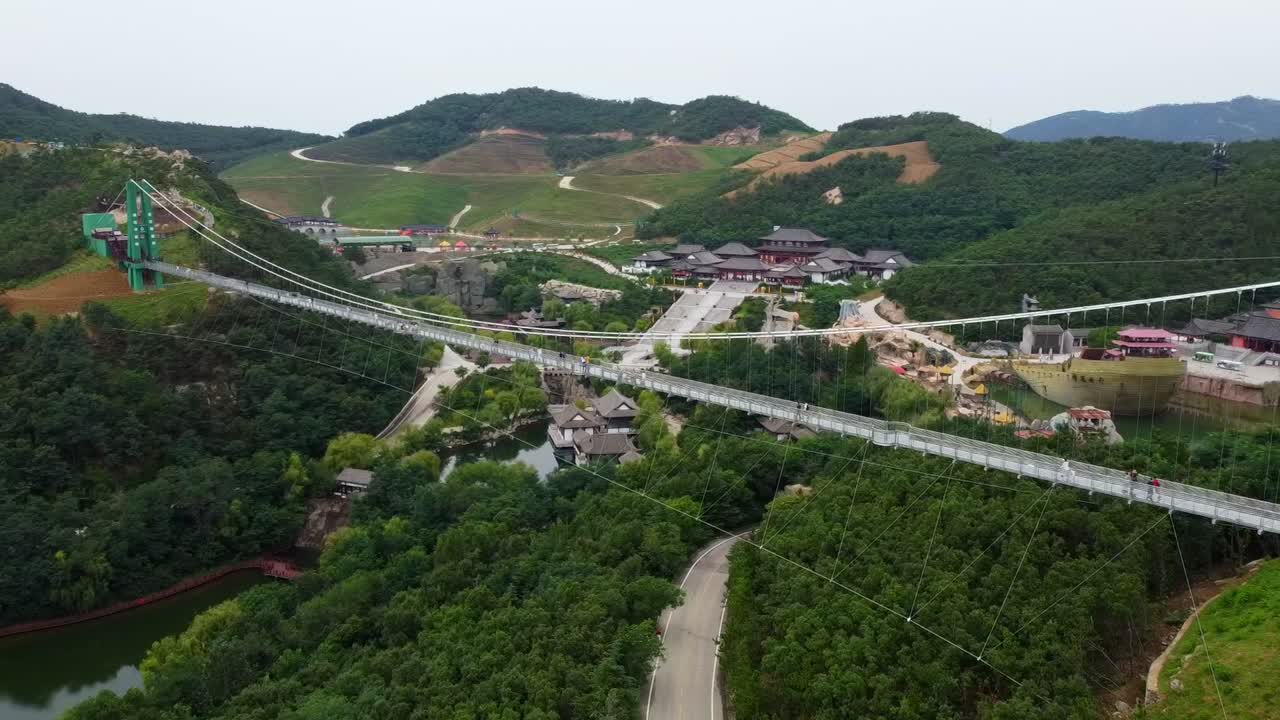 Spectacular aerial view of suspension glass bridge at Huaxiacheng theme Park in Weihai, China