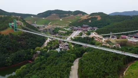 Espectacular-Vista-Aérea-Del-Puente-Colgante-De-Cristal-En-El-Parque-Temático-Huaxiacheng-En-Weihai,-China