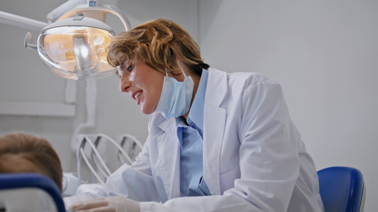 Dentist smiling little patient after treatment in dentistry office closeup