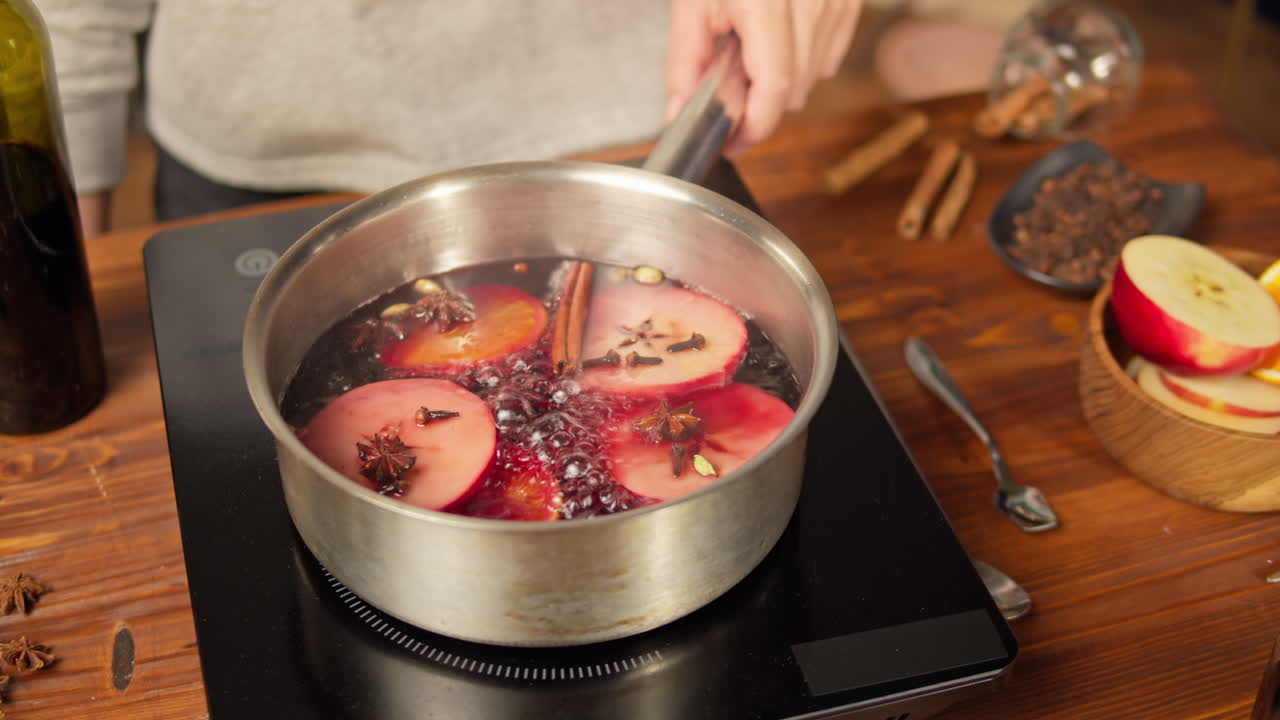 Vin brulé che sobbolle con mele e spezie su un piano cottura a induzione