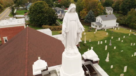 An-aerial-view-of-a-statue-of-the-Virgin-Mary-on-top-of-a-Catholic-Church-in-upstate,-NY