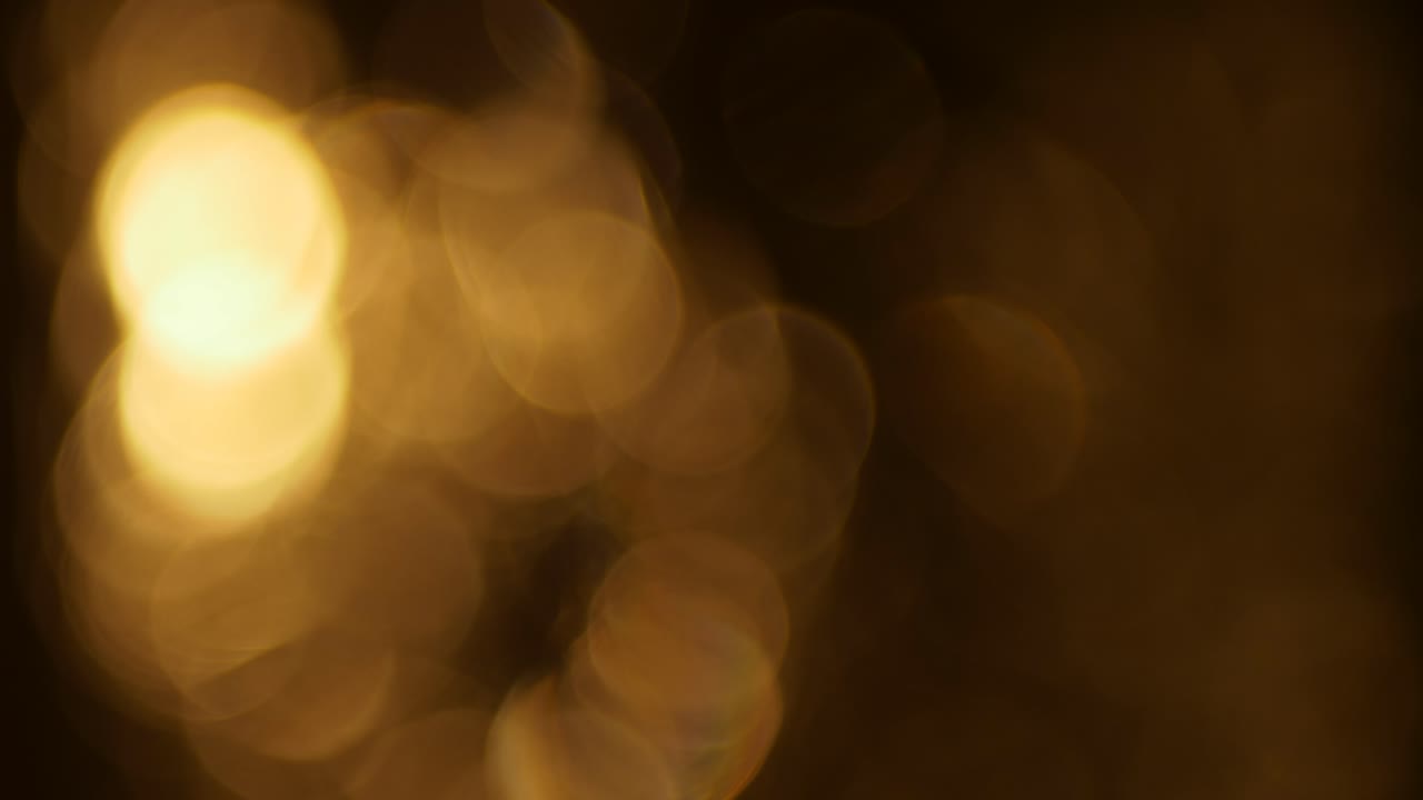 Cerchi di luce bokeh dorati scintillanti su sfondo scuro