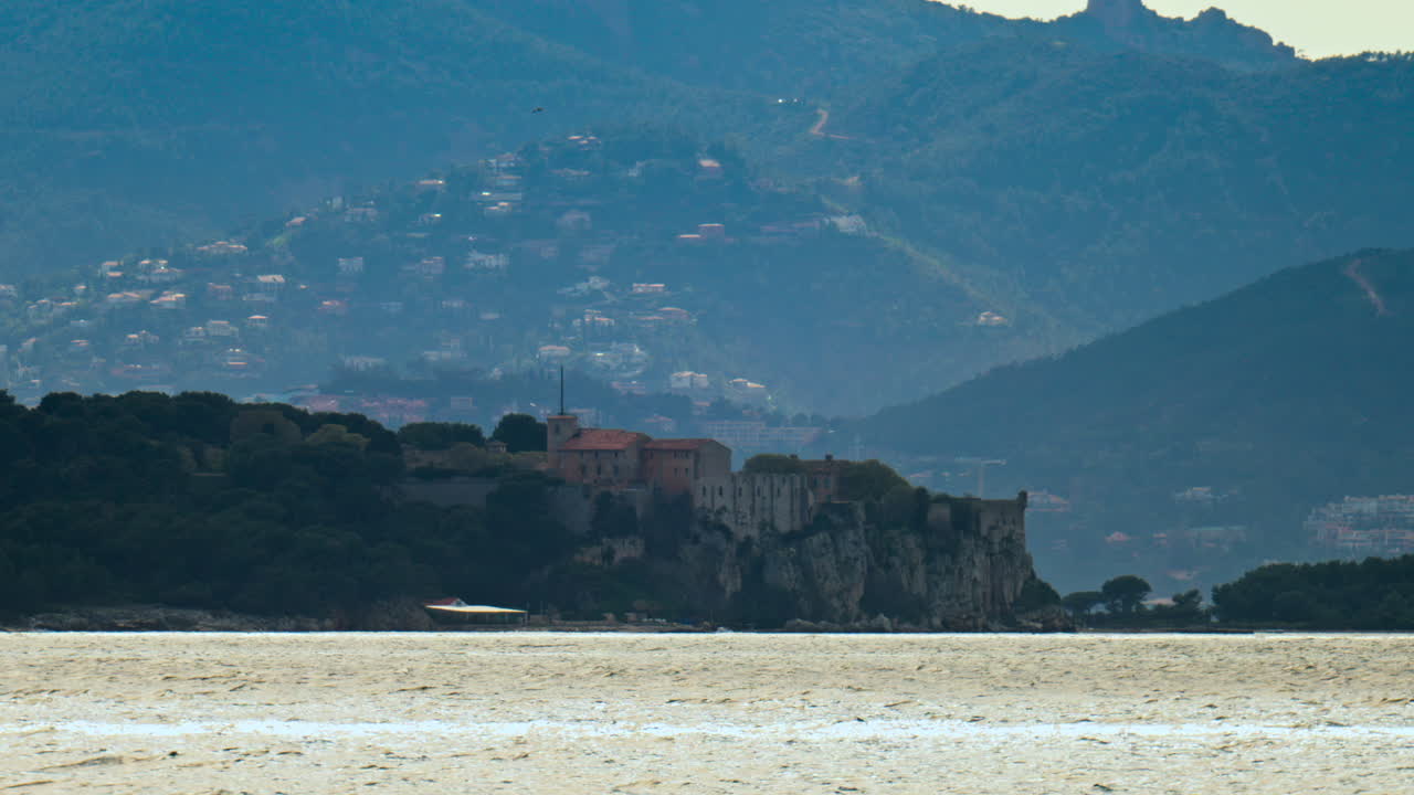 Distant view of multiple buildings on cliffs with many small white houses on hills and mountains in the background