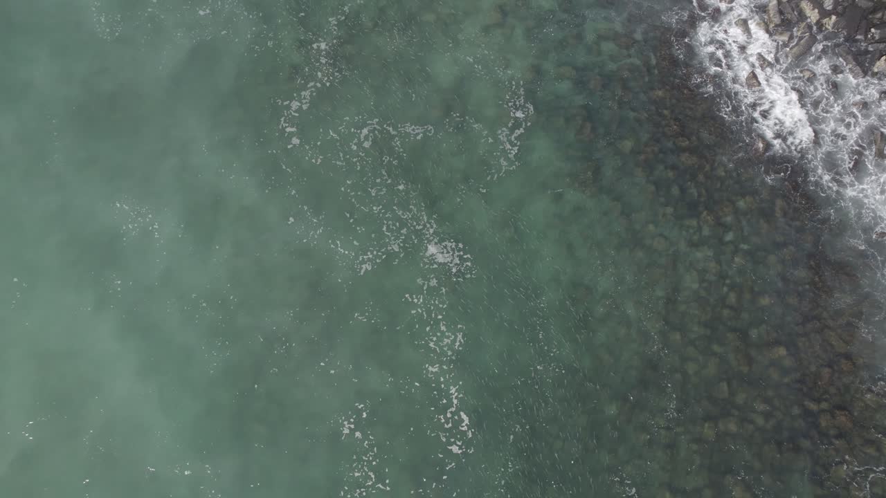 aérea sobre las claras aguas azules del mar de coral con olas salpicando en la playa de burleigh en gold coast, queensland