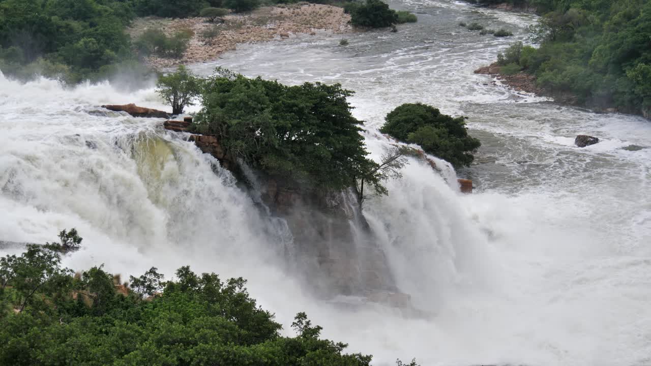 el agua de inundación brumosa liberada de la represa eléctrica fluye sobre una cascada rocosa