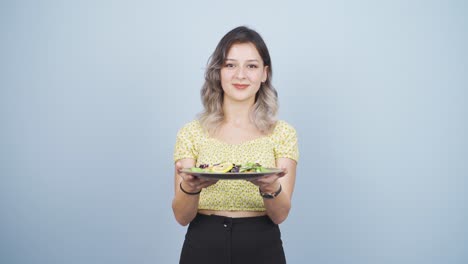 the person holding a plate of salad is laughing.