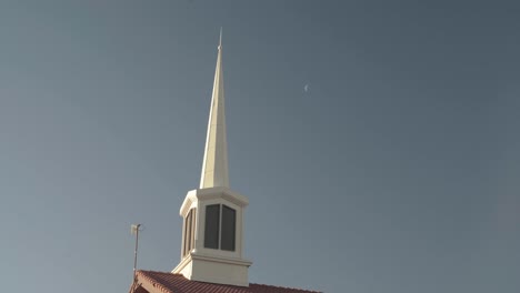 Aguja-Mormona-Del-Edificio-De-La-Iglesia-En-El-Cielo-Azul-Con-Luna-Distante-En-El-Fondo-4k