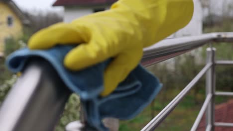 Primer-Plano-De-La-Mano-Femenina-Usando-Un-Paño-Húmedo-Y-Un-Spray-Desinfectante-Para-Manos-Para-Limpiar-La-Barandilla-De-La-Escalera-De-Acero-Inoxidable