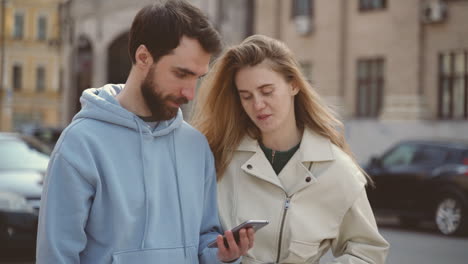 un jeune couple regardant quelque chose sur l'écran du téléphone portable