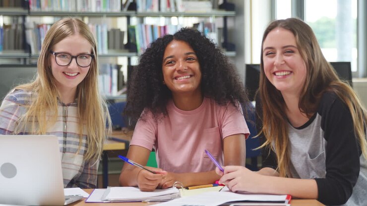 Portrait Of Three Female College Students Working In Library