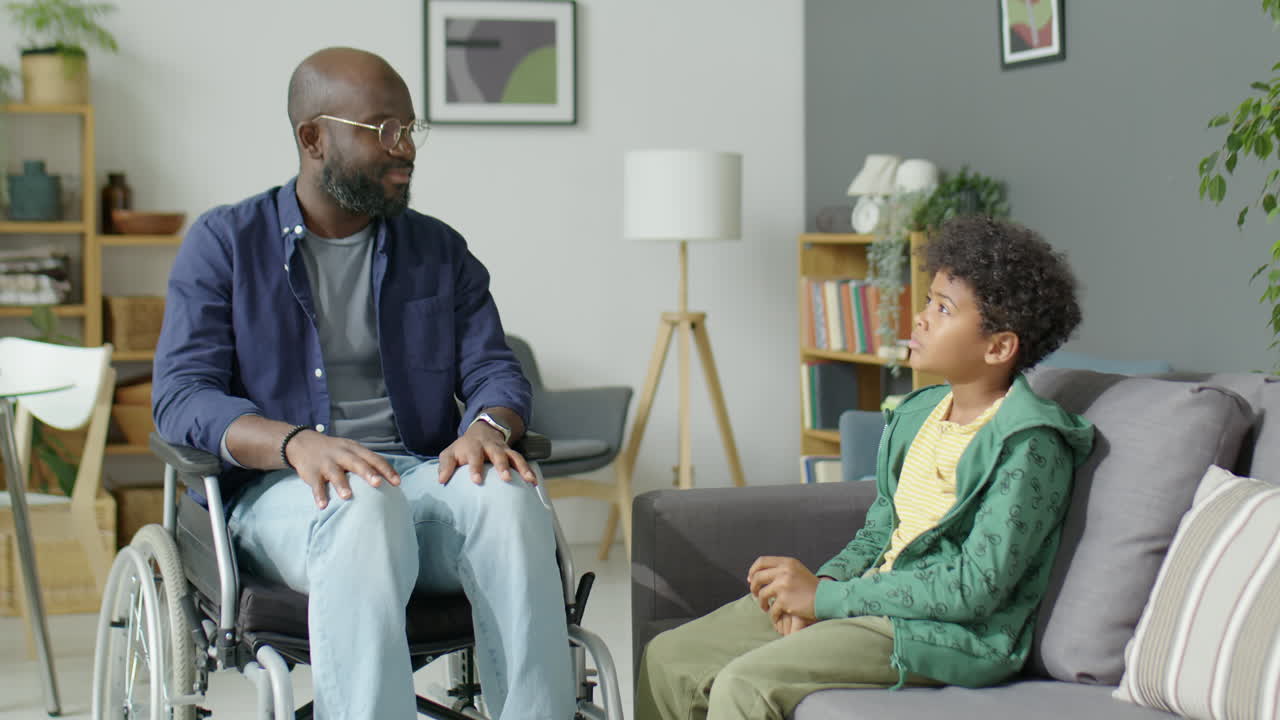 Black Man in Wheelchair Speaking with Son at Home