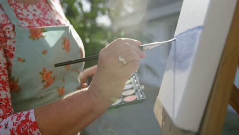 senior woman painting on canvas in the garden 4k