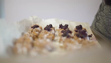 slow dolly of woman laying out jam across multiple cookies on baking sheet