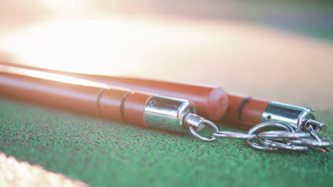 Red-Wooden-Nunchucks-With-Metal-Chain-Lies-On-Floor