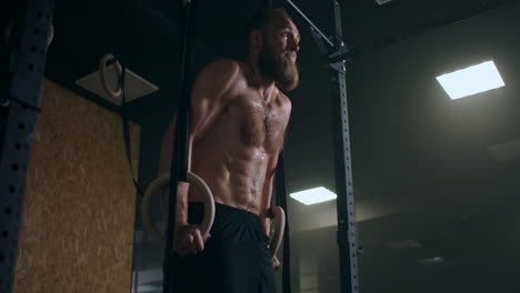 Strong-bearded-male-athlete-performs-push-ups-on-gym-rings-in-slow-motion-in-the-gym