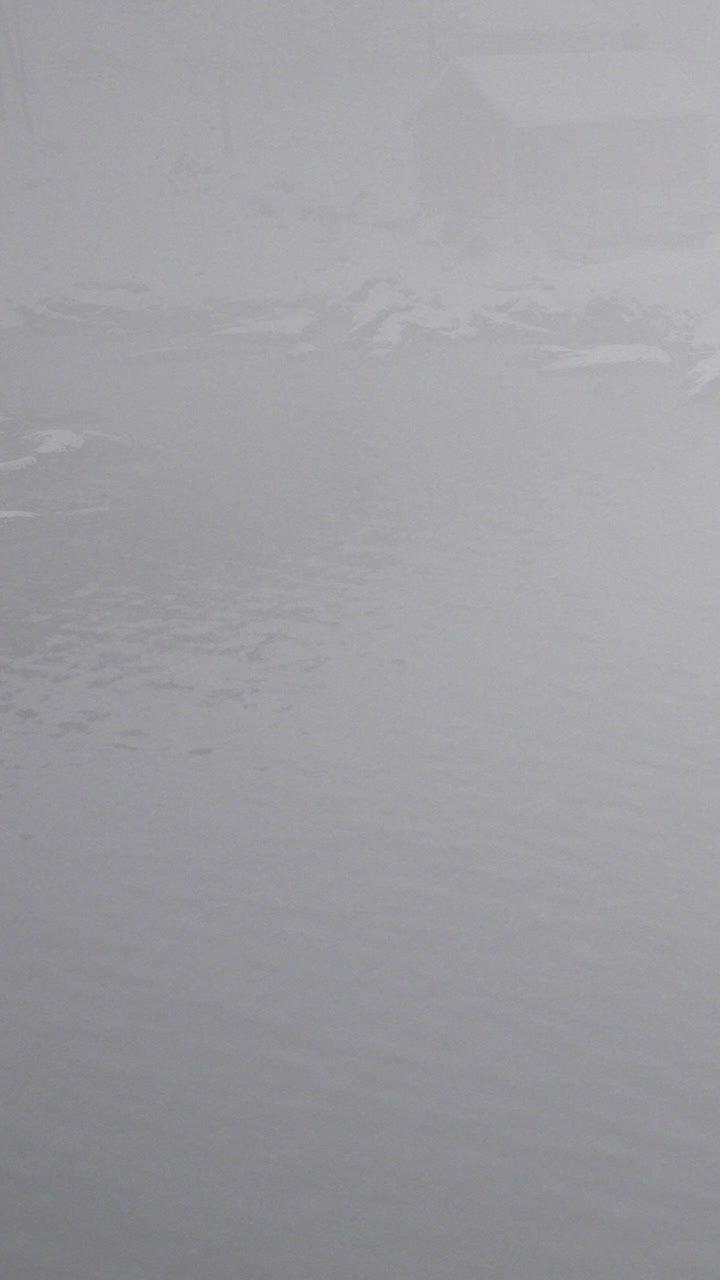 Fog covers a lake with ripples in water during early morning hours
