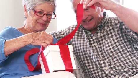 cute mature couple opening a gift on the couch