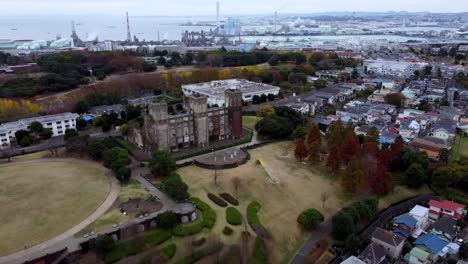 A-historic-castle-amidst-autumn-trees-in-a-suburban-area,-aerial-view