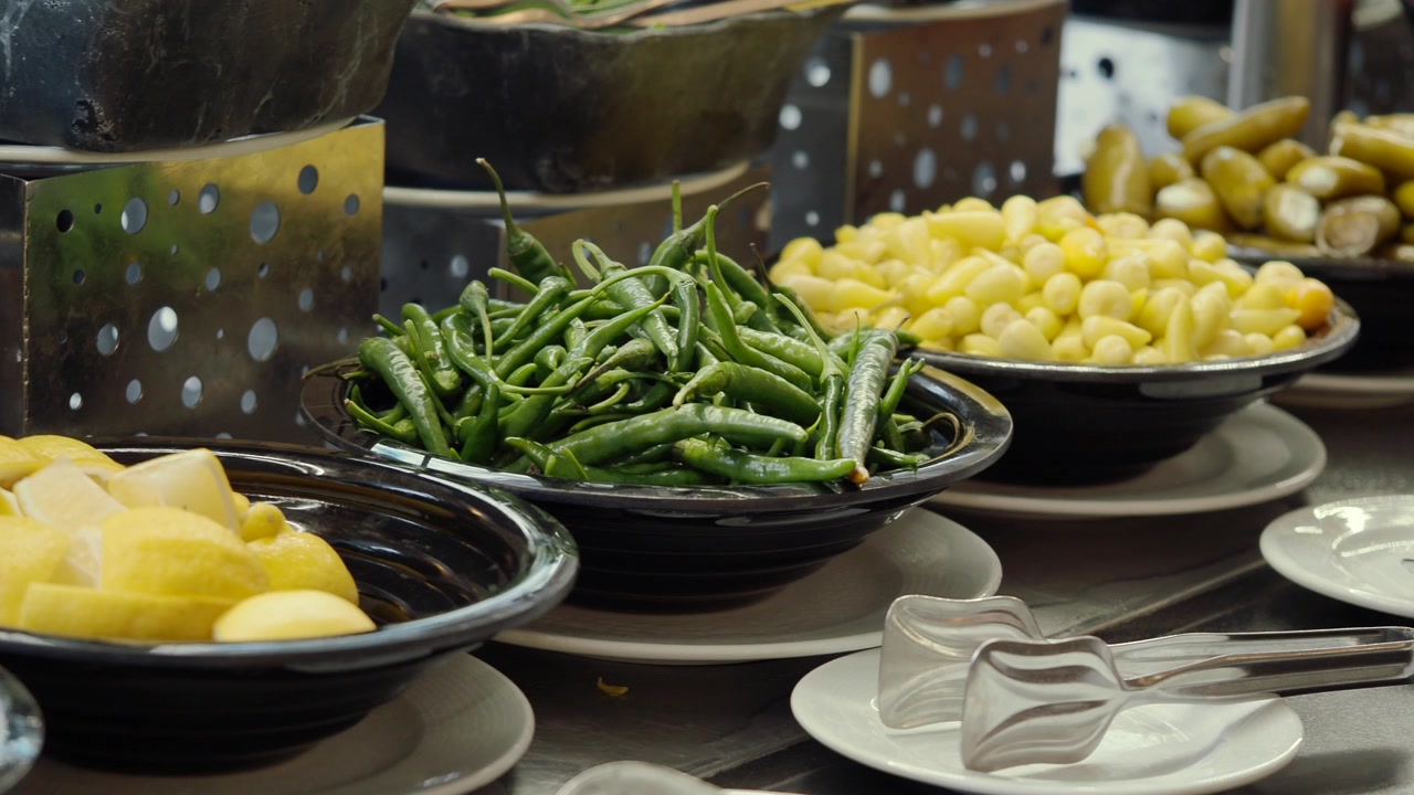 Variety of Pickled Peppers and Fresh Lemons on a Buffet Line