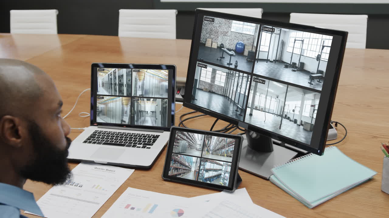 oficial de seguridad afroamericano viendo las vistas de las cámaras de cctv en pantallas de computadora, cámara lenta