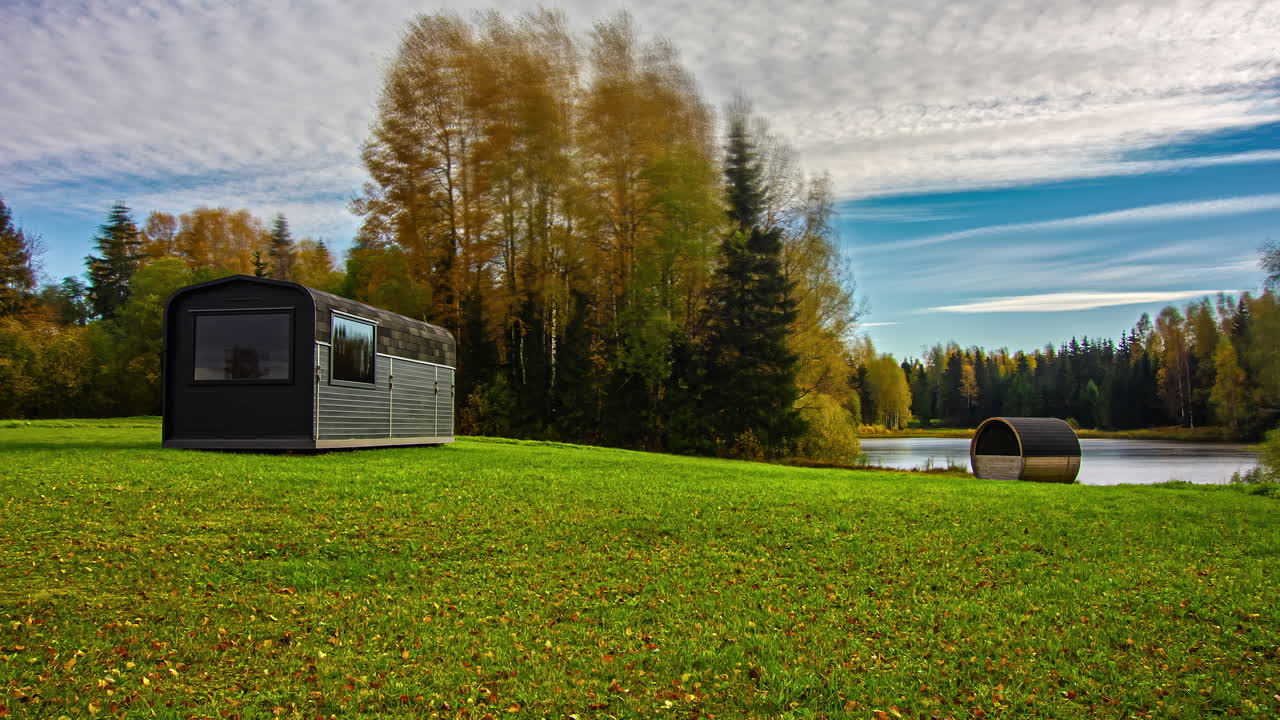 Bellissima ripresa in timelapse di un paesaggio autunnale con una baita in legno e una sauna a botte sulle rive del lago di giorno