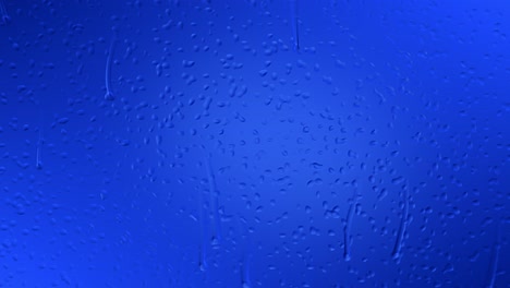 an animation of raindrops slowly gliding down on the window glass against a moody blue gradient background with highlights that are reflecting on the droplets