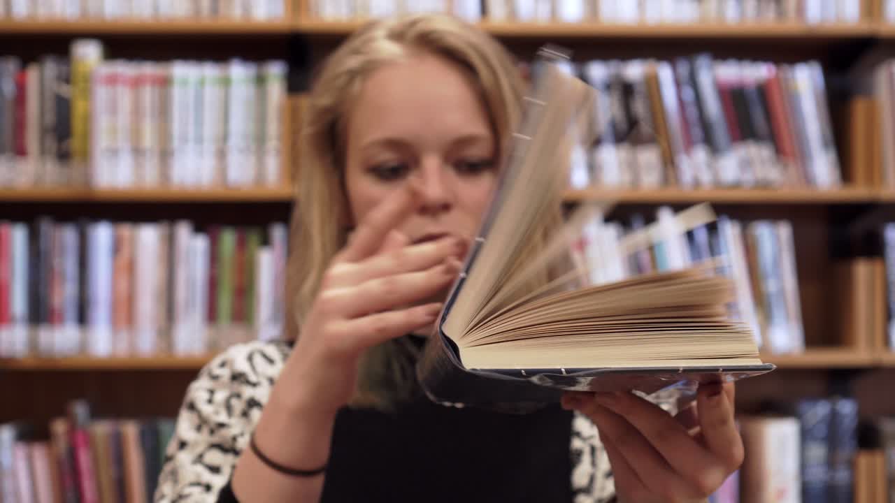 una joven hermosa está cerrando un libro abierto, una toma lateral, una mirada neutra