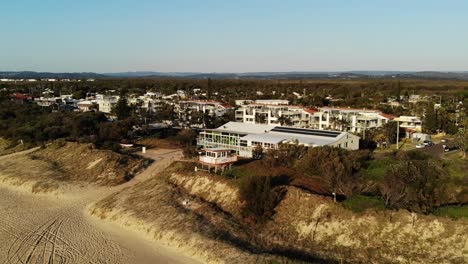 Waves-on-the-white-sands-of-Australia,-sunrise-with-the-surf-club-in-the-background