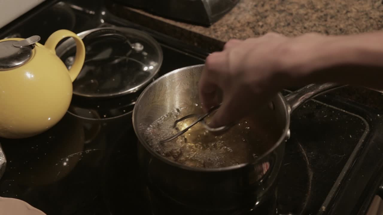 A Man Frying Breaded Meat In A Boiling Pot With Oil - Close Up Shot