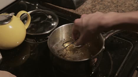 a man frying breaded meat in a boiling pot with oil - close up shot