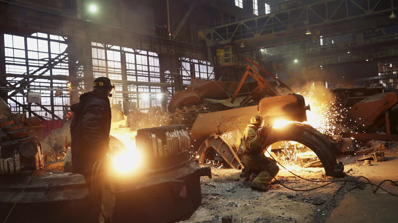 Metal Workers Welding and Repairing Heavy Equipment in Industrial Factory