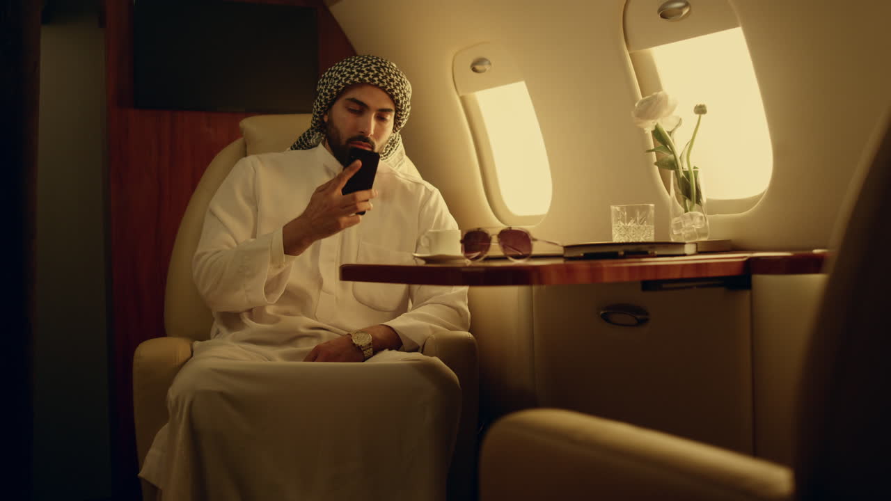 millonario hablando por teléfono celular en el avión. hombre árabe feliz llamando.
