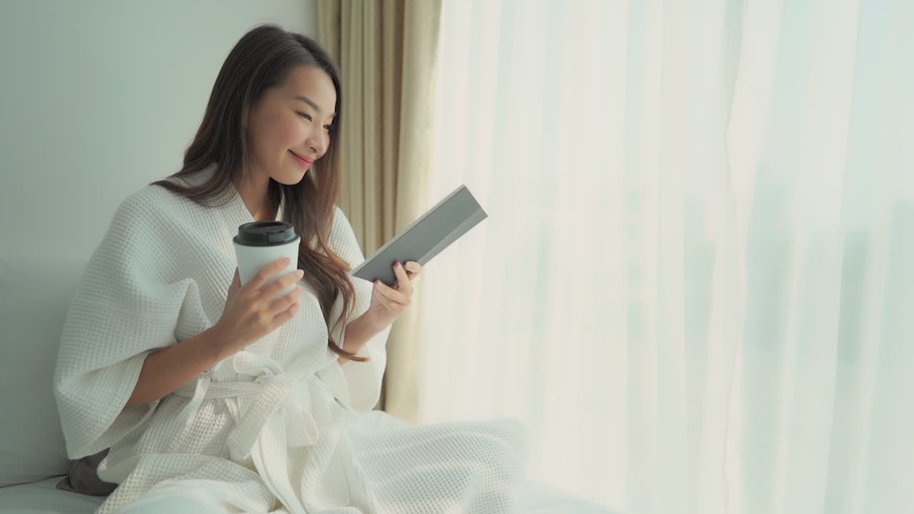 A woman reading a book in her robe whilst having a cup of coffee in a cozy living room