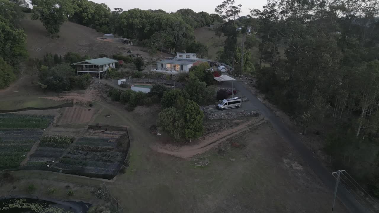 Droneoptagelse daler ned mod smukt hus på bjergskråning med pool på landejendom