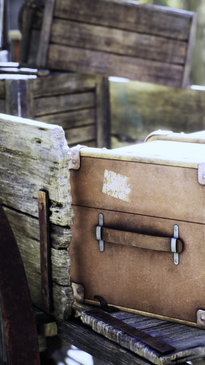 Old travel trunk resting on a wooden cart in a rustic setting