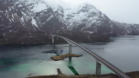 Flying-over-Lofoten-Reine-mountain-peaks-overlooking-picturesque-wintry-blue-ocean