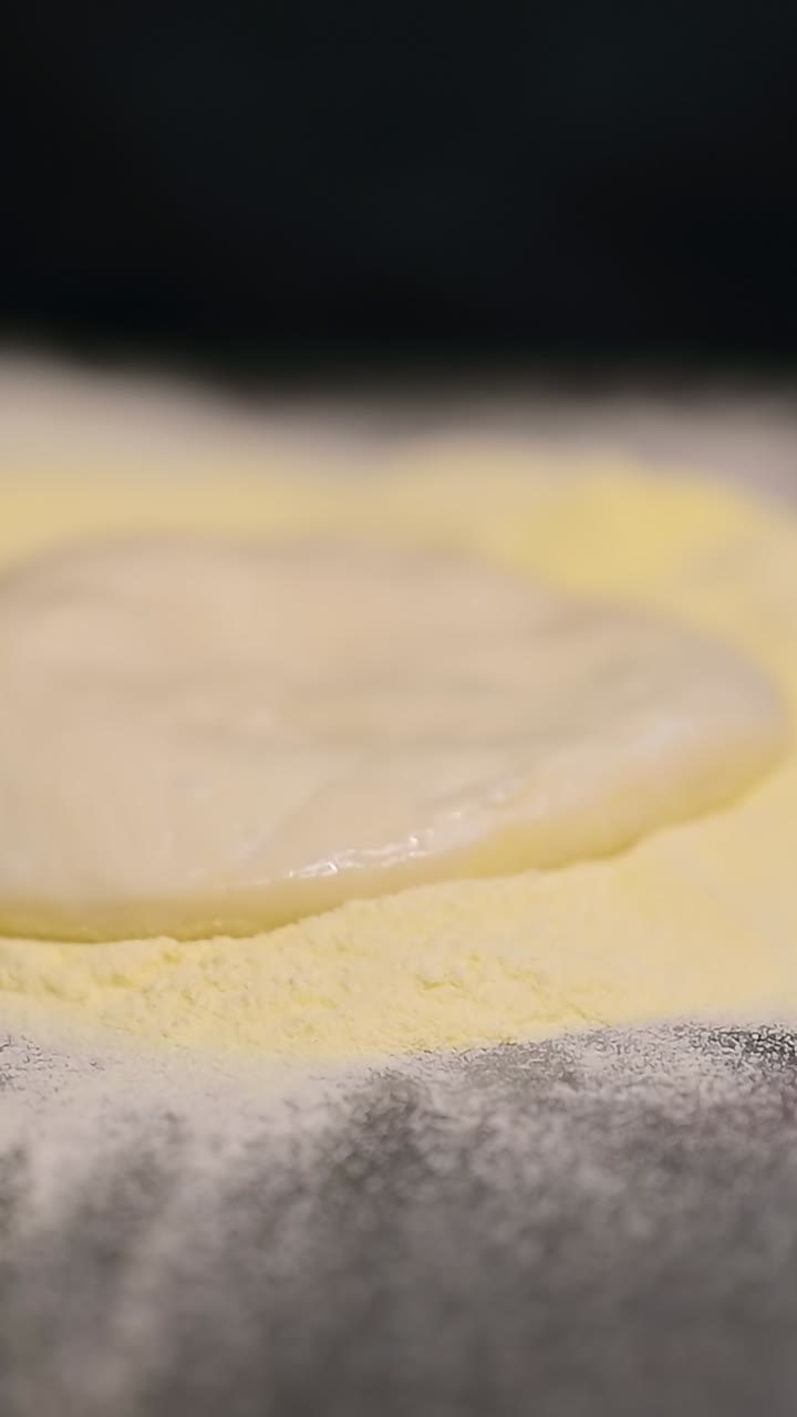 Chef rolling out pizza dough. Italian pizza chef forming the dough on a floured surface
