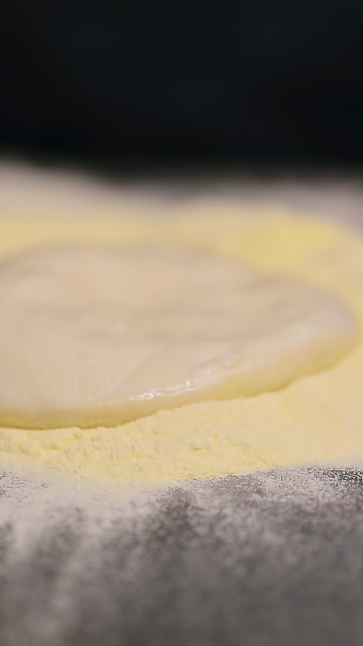 Chef rolling out pizza dough. Italian pizza chef forming the dough on a floured surface