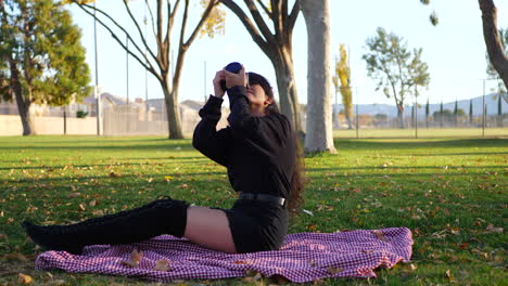 una bella fotógrafa milenaria tomando fotos con una cámara digital sobre una manta en un parque rodeado de hojas de otoño