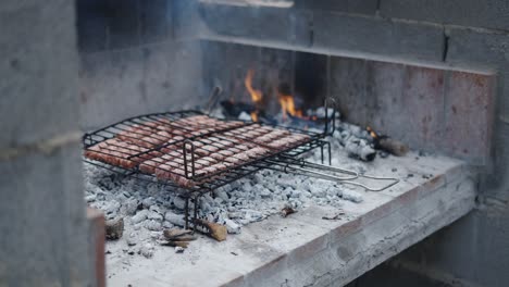 man grilling sausages on an outdoor charcoal barbecue