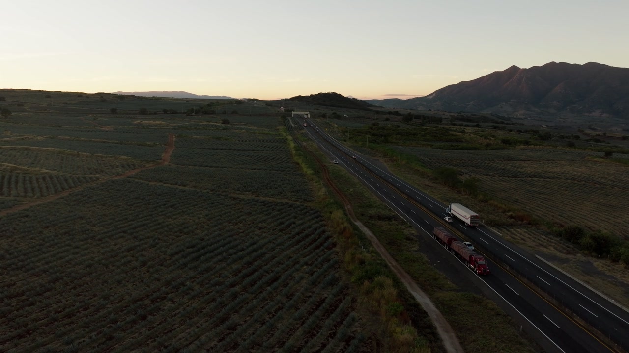 DRONE: DOLLY IN SHOT OF A HIGHWAY BETWEEN AGAVE FIELDS IN JALISCO