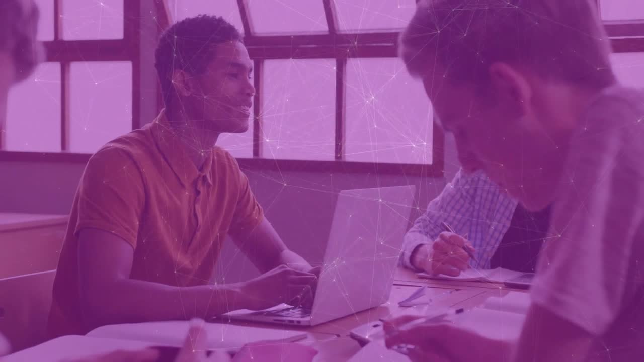 Male at laptop glancing at peers, speaking and smiling, sharing solution for study session