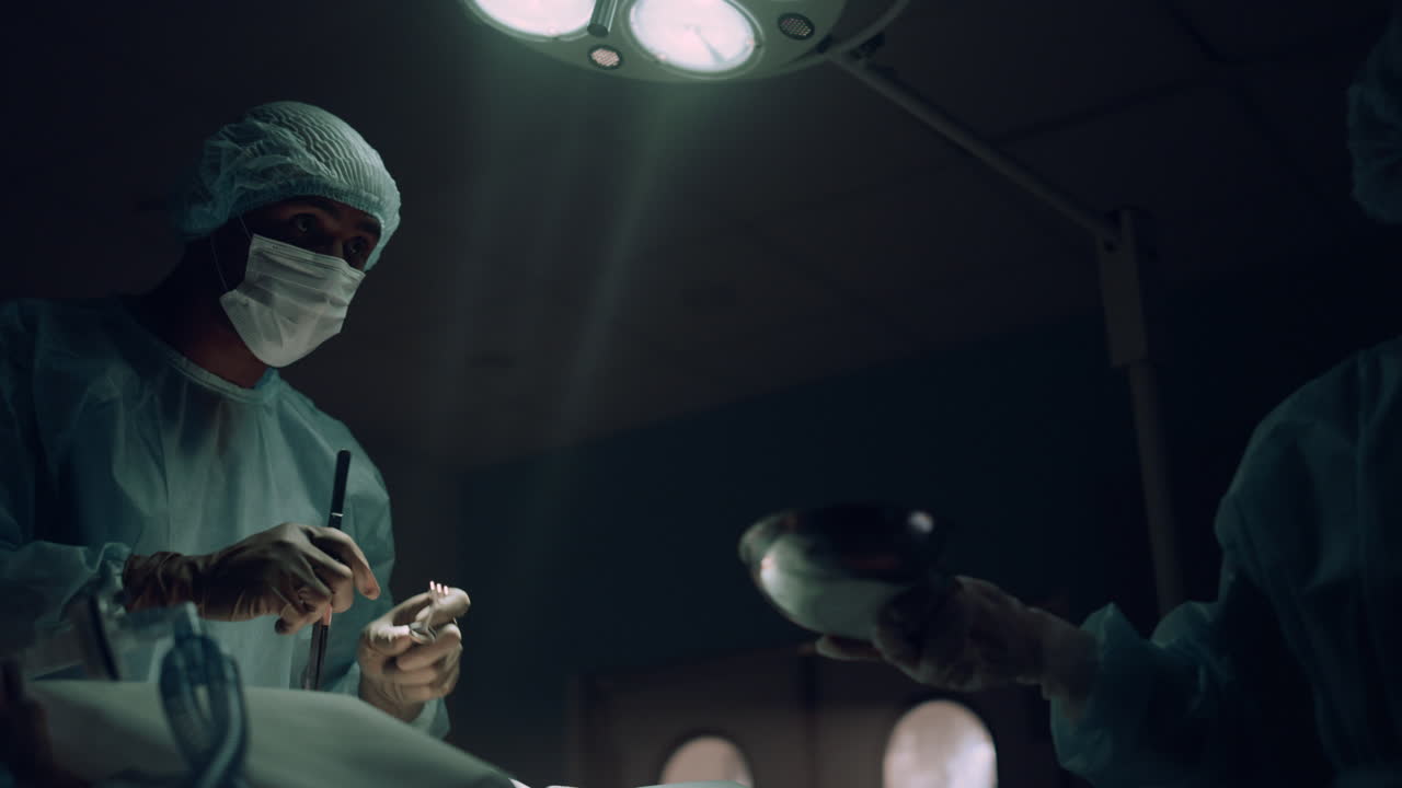 Alvorlig kirurg udfører kirurgisk behandling på operationsstuen. Medicinsk teamsamarbejde.