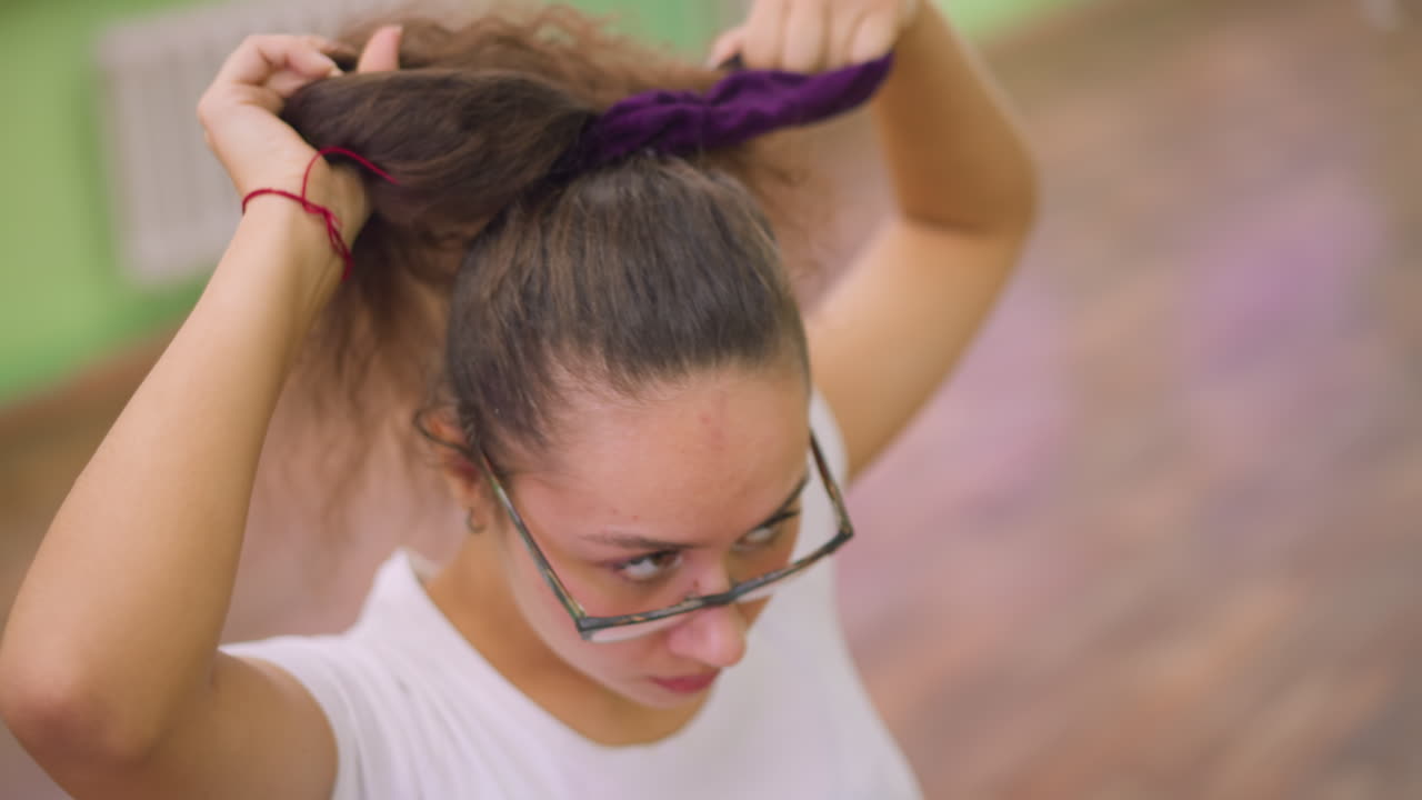 Close view of woman packing hair with hair packer hands gathering strands securing style under soft studio light blurred background intimate grooming motion showing texture movement confident focused