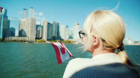 una mujer con la bandera de canadá mira el paisaje urbano de toronto desde el barco. concepto de turismo en canadá