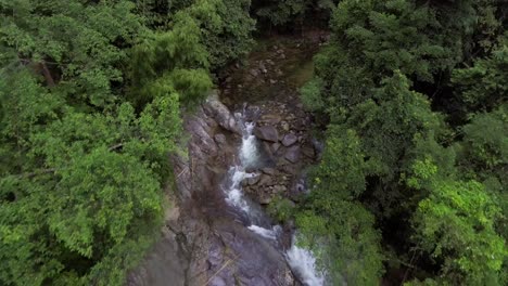 drone flying over a flowing river in the rainforest in malaysia