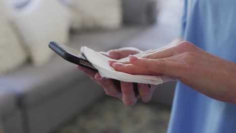 sección media de una trabajadora de la salud limpiando su teléfono inteligente con un pañuelo