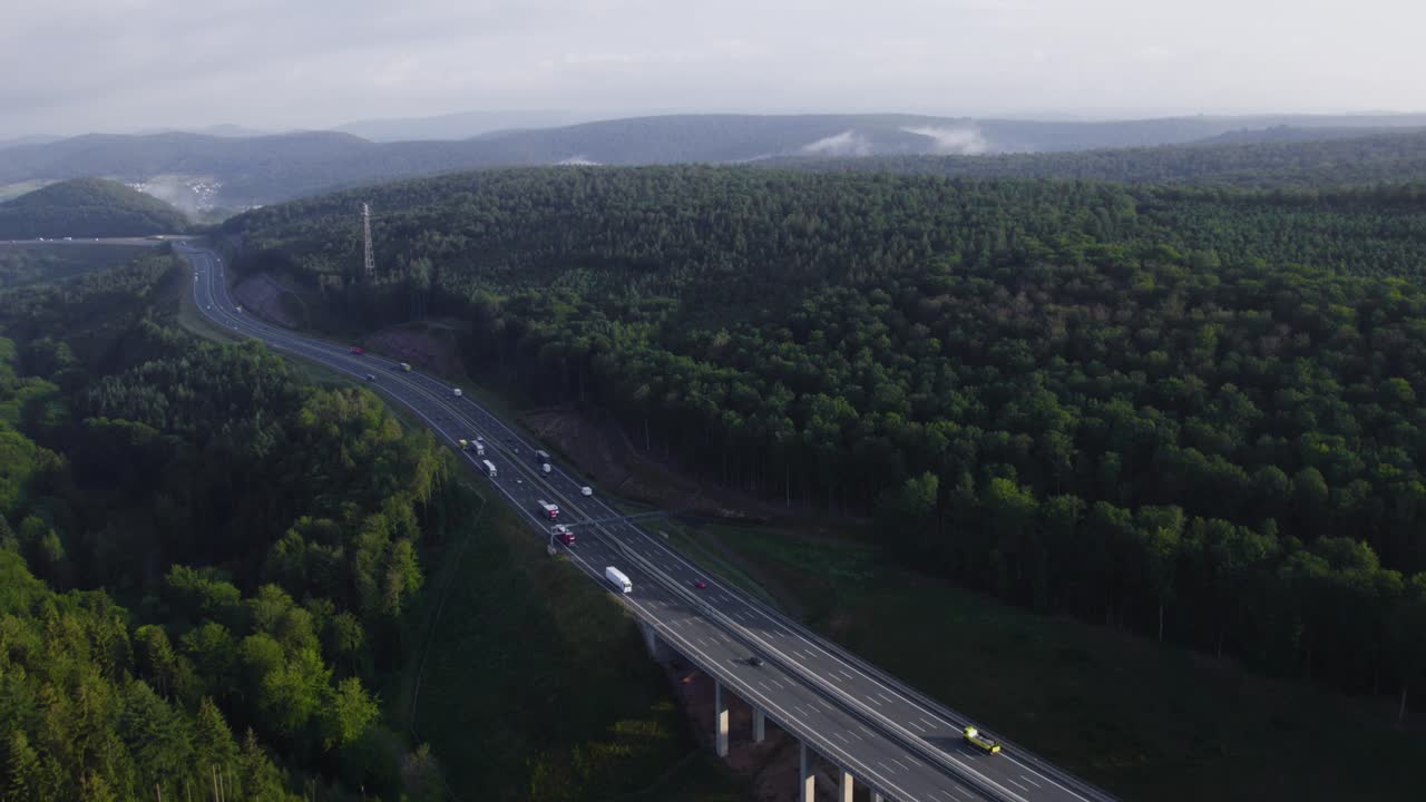 Long highway where many vehicles cross it in a forest setting. In Weibersbrunn Germany, Europe. Drone aerial 4K footage.